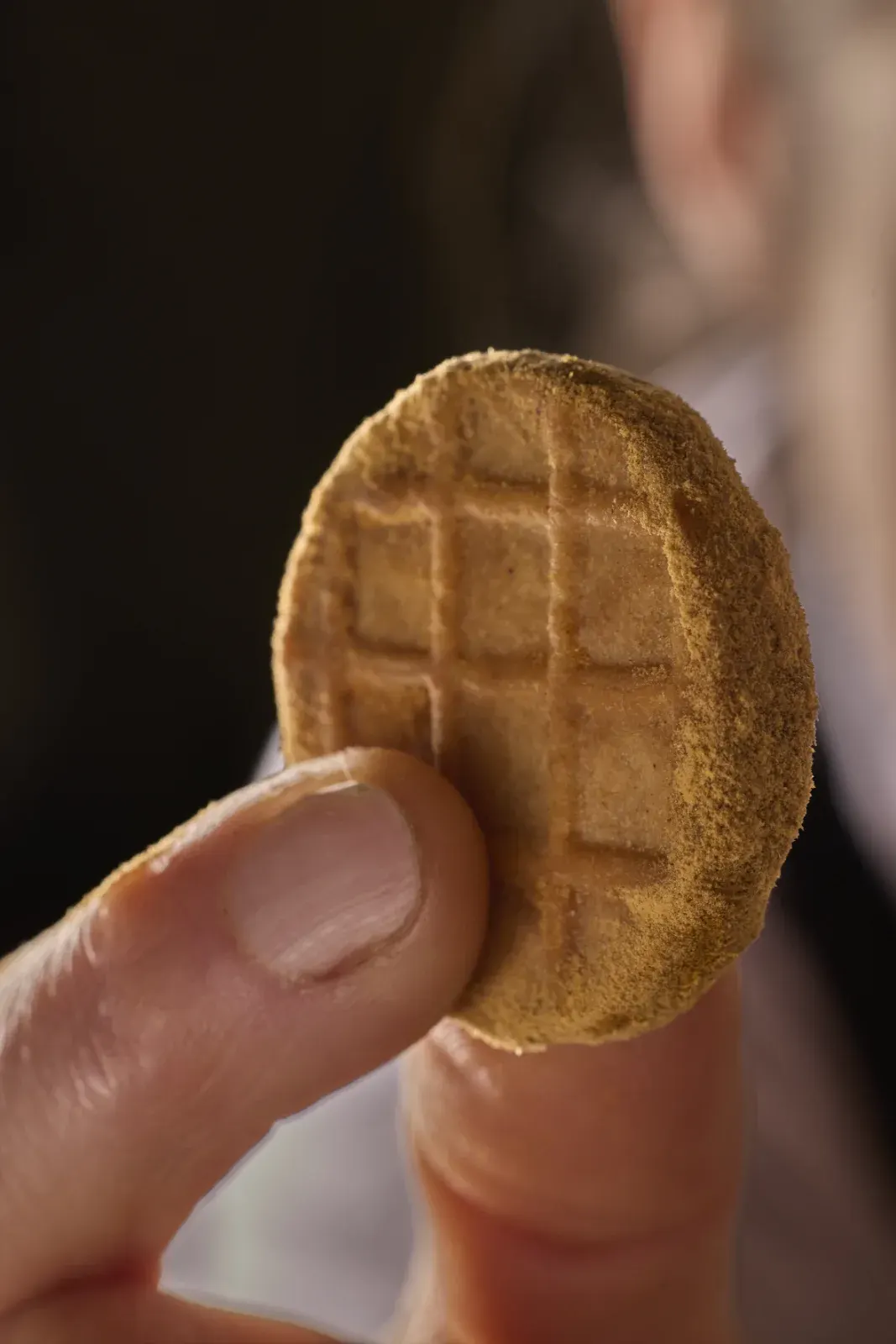 Un gofre fino sostenido entre los dedos, uno de los bocados dulces de la casa