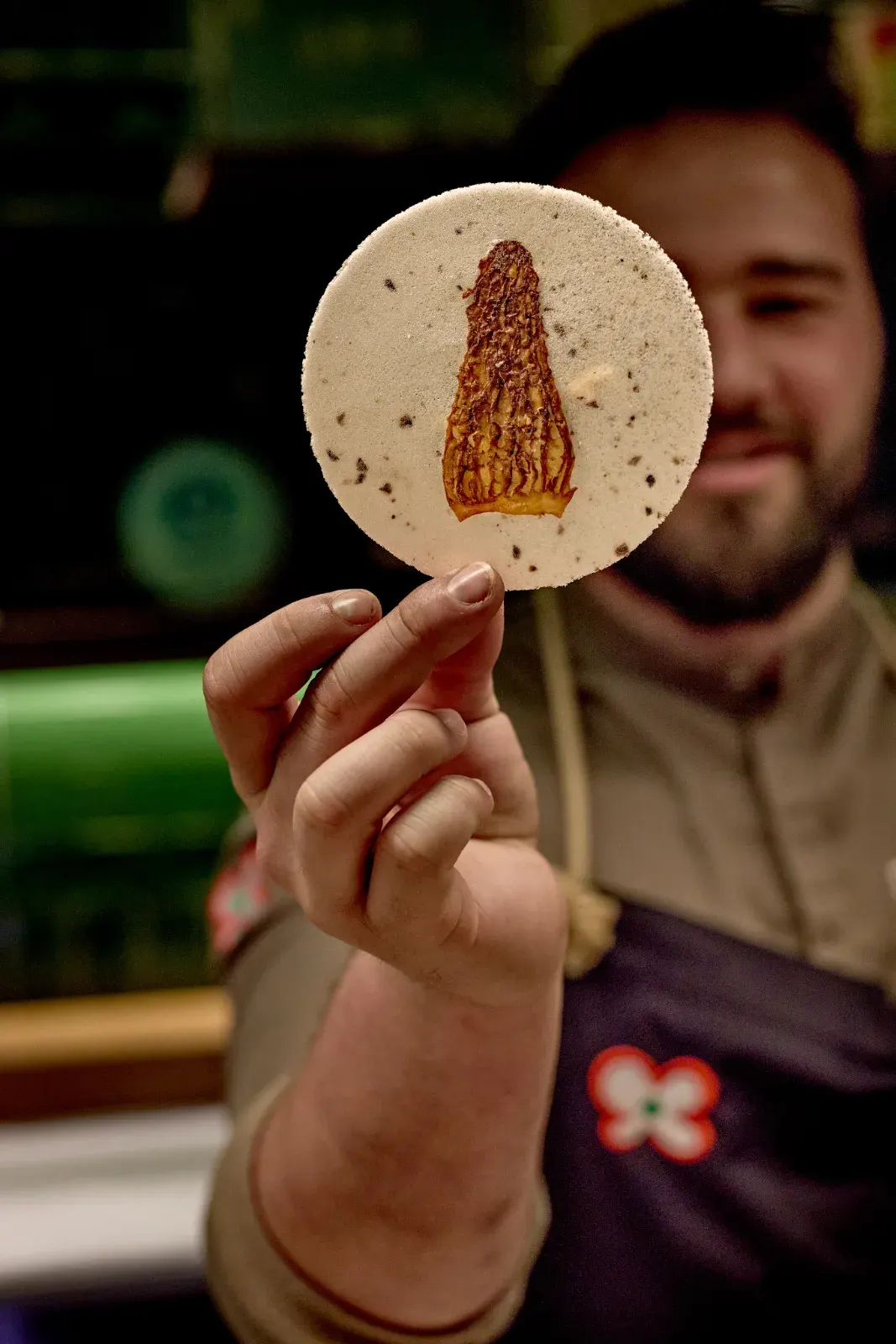 Un cocinero sostiene una galleta fina con una colmenilla impresa en el centro
